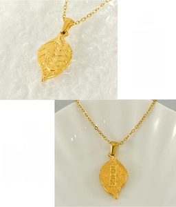 Détails macro d'un pendentif feuille dorée orné de motifs de pièces chinoises
