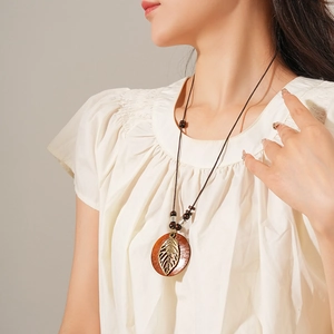 Détail du collier bohème avec pendentif feuille ajourée et perles en bois sur cordon