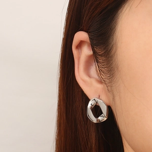 Dettaglio di orecchini geometrici in titanio argento indossati per un look moderno e chic