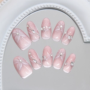 Handmade pink gradient press-on nails with floral art and 3D rhinestones on a mirror tray