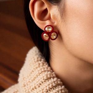 Detail of vintage red velvet oval stud earrings with amber stones on model for winter look