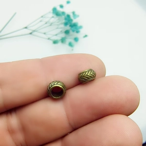Close-up of bronze alloy spacer beads with herringbone pattern on a finger