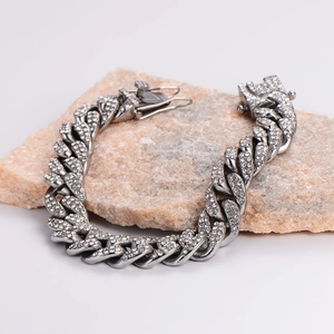 Silver stainless steel Cuban link bracelet with sparkling rhinestones on stone background