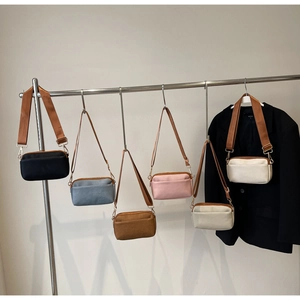 Multiple colors of minimalist nylon crossbody bags hanging on a display rack