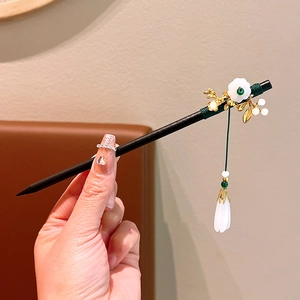 Detailed view of handmade sandalwood hairpin with white flower and elegant silk tassel