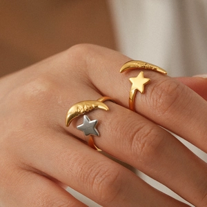 Close-up of adjustable 18K gold star and moon rings on model's hand with fine details