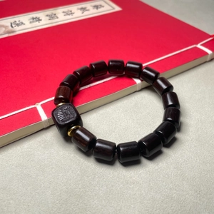 Gros plan du bracelet en bois de santal avec sculpture de voilier sur un livre