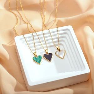 Three heart pendants in green, black, and white shell on delicate gold chains