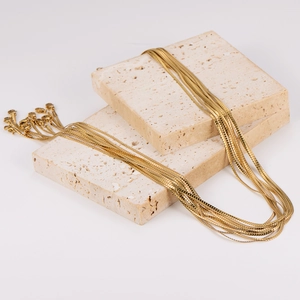 Elegant 2mm golden snake chain necklaces draped over stone blocks on white background