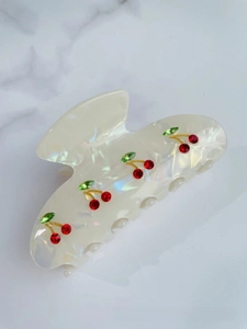 Detail shot of pearl white acetate hair claw clip with red rhinestone cherry patterns
