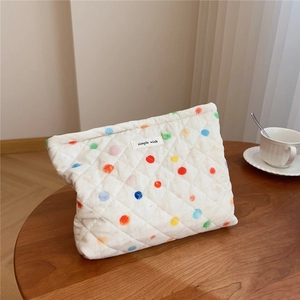 Detailed macro of a quilted cotton makeup bag with colorful polka dots and a fabric label