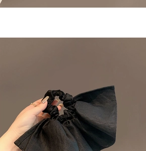 Detailed close-up of a large black textured fabric bow scrunchie on a ponytail
