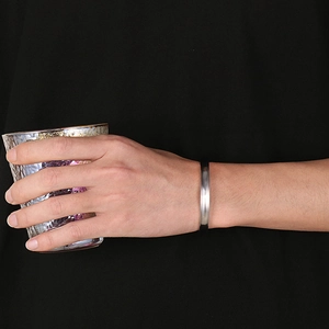 Minimalist silver stainless steel open bangle with concave groove on a model's wrist