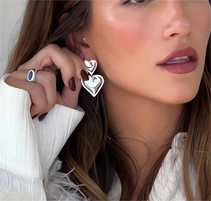 Close-up of double heart drop earrings in silver finish worn by a model