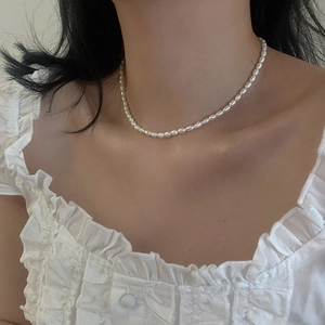 Close-up of minimalist white freshwater pearl choker on neck with vintage blouse