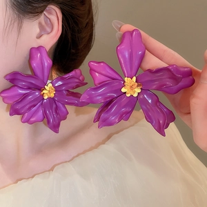 Detail view of large purple floral acrylic earrings with yellow beaded centers on model