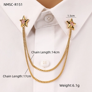 Detail of gold star collar pin with pink gemstone and layered chains on shirt