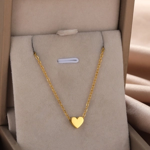 Macro shot of gold heart pendant necklace displayed on silk fabric inside a premium gift box
