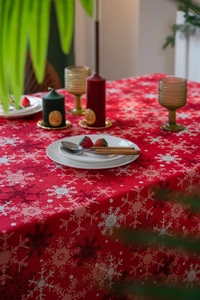 Detail showing red Christmas tablecloth fabric with white snowflake pattern in home setting