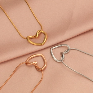 Detailed view of three heart pendant necklaces in gold, rose gold, and silver on pink silk