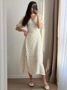 Détail d'une robe fleurie en coton avec col en V, manches bouffantes et taille nouée