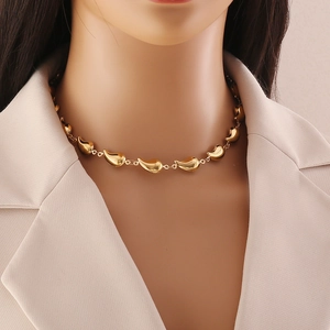 Close-up of gold metal necklace with teardrop pendants worn by model on beige background