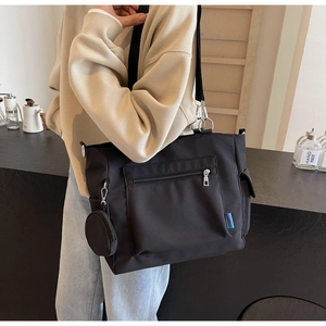 Detail of black canvas tote bag with front zipper pocket and round coin purse attachment