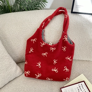 Gros plan du sac cabas en peluche rouge avec nœud brodé blanc et doublure à carreaux