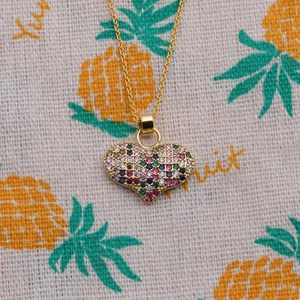 Minimalist gold heart pendant necklace with multicolored zircon stones on pineapple fabric