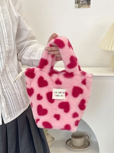 Sac à main en peluche rose avec motifs de cœurs et texture douce dans une scène de vie