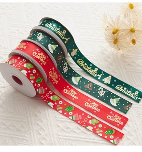Detail of red and green Christmas ribbons with gold Merry Christmas print and festive icons