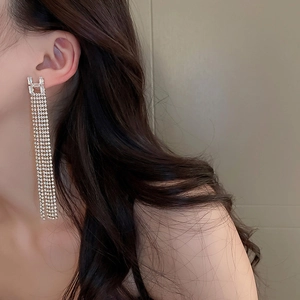 Close-up of dangling emerald rhinestone leaf tassel earring worn by a model