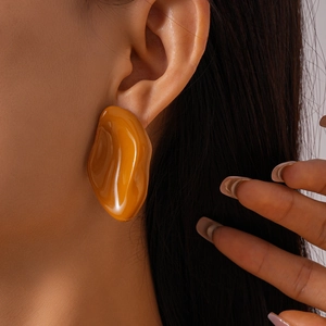Close-up of irregular amber resin earring worn by model showing smooth glossy texture