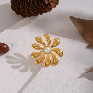 Elegant gold flower ring with center pearl on white stone texture background