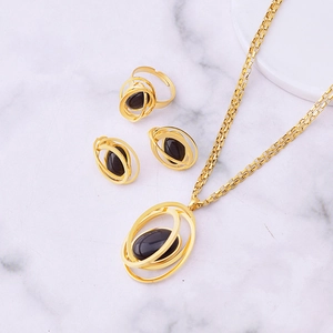 Golden jewelry set with layered rings and black stones on marble background