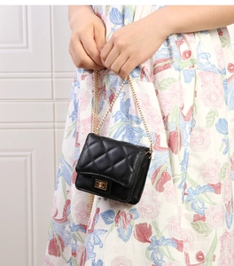 Vue détaillée d'un mini sac noir matelassé chic avec chaîne dorée et fermoir élégant.