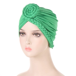 Dettaglio di un turbante verde con design a fiore intrecciato indossato da un modello