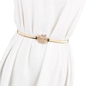 Détail d'une ceinture dorée à ressort avec une boucle en strass en forme de pomme