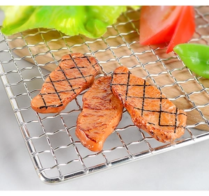 Detailed view of three PVC artificial roast steaks with realistic grill marks on a wire rack