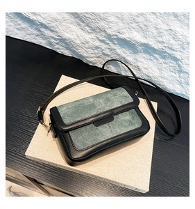 Close-up of minimalist black and green PU leather crossbody bag on a textured book