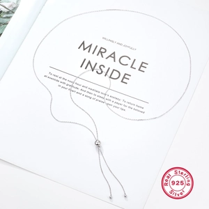 Detail of S925 sterling silver Y-shaped tassel necklace with metal beads on magazine