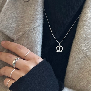 Close-up of a 925 sterling silver pretzel heart necklace and minimalist ring set for women