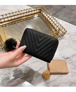 Detail shot of black quilted faux leather wallet with gold zipper and fur pompom