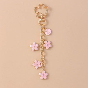 Detail of gold cherry blossom keychain with pink enamel petals and a letter K charm