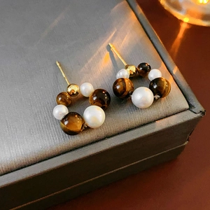 Detailed close-up of French vintage earrings with white pearls and brown tiger eye beads