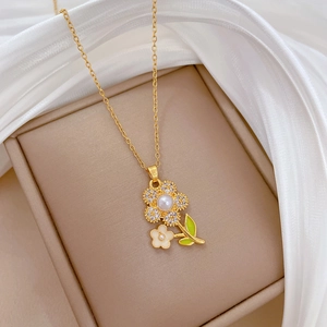 Detail of flower pendant necklace with white enamel petals and green leaves in a gift box