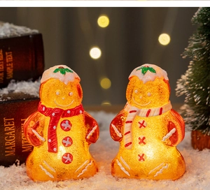 Close-up of glowing LED gingerbread man figurine on snow with festive bokeh background