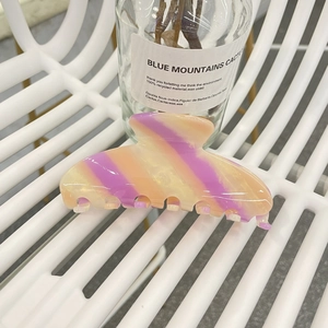 Macro detail of large acetate hair claw clip featuring vibrant purple and orange stripes