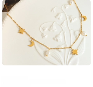 Detailed shot of gold necklace with star, moon pendants and natural freshwater pearls
