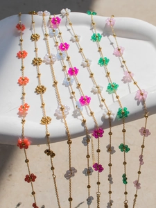 Detailed macro of colorful beaded flower necklaces and bracelets on a white tray